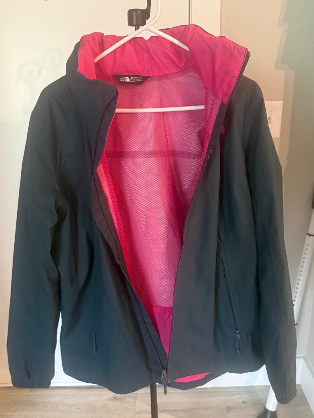 The North Face hooded windbreaker jacket in a muted blue-gray with bright pink
